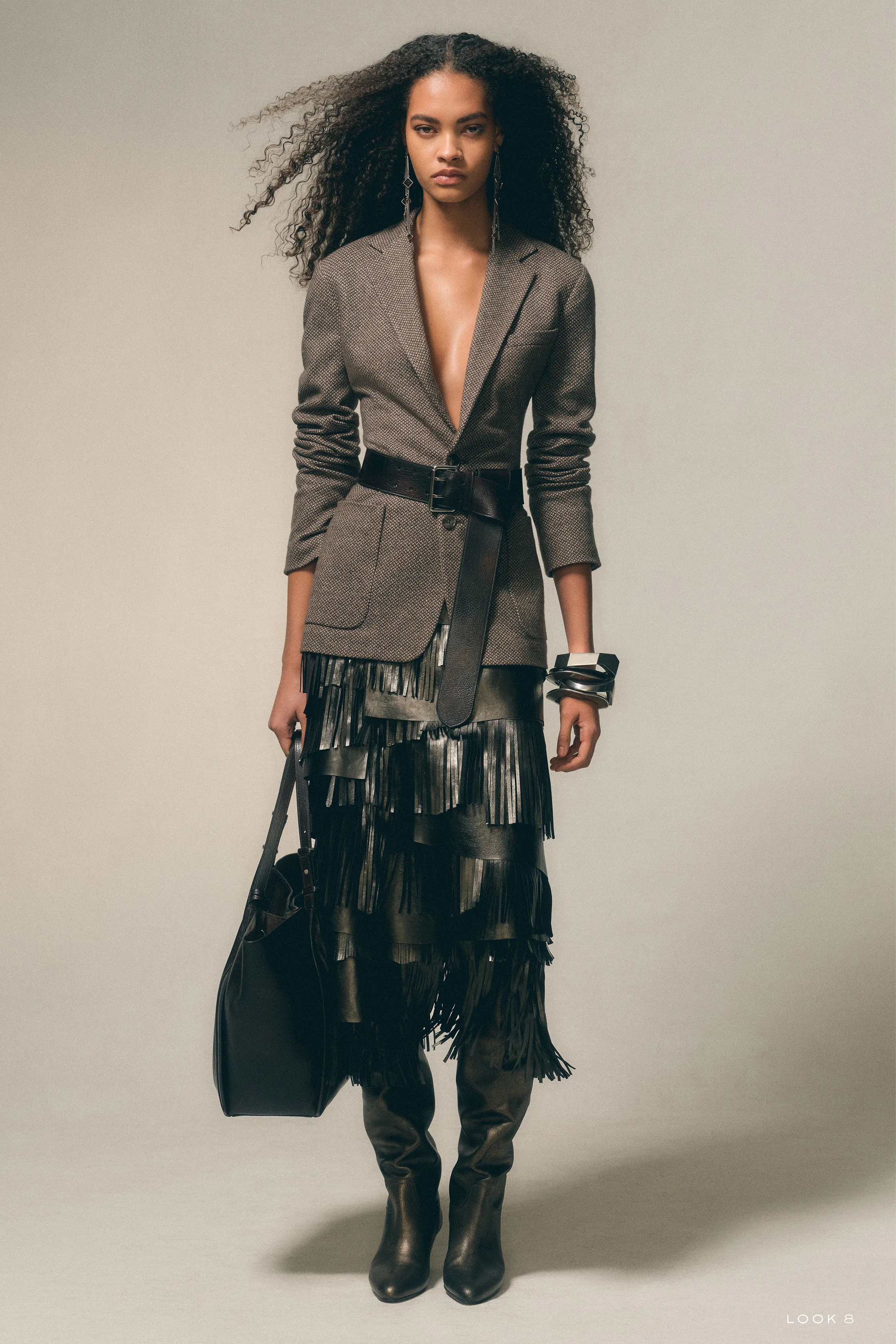 Пиджак с текстурой и юбка с бахромой, создающие динамичный образ, дополненный крупными украшениями