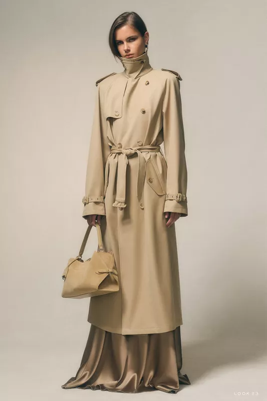 Классический бежевый плащ с поясом и высокими воротниками, гармонирующий с блестящей юбкой, создает утончённый образ