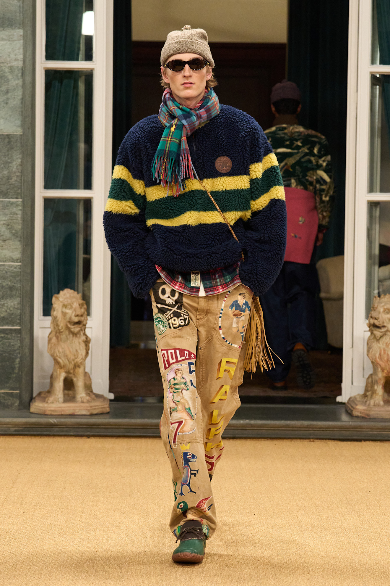 Объемный свитер с полосами и яркими нашивками, дополненный фланелевой рубашкой и необычными брюками, задает стильный тон