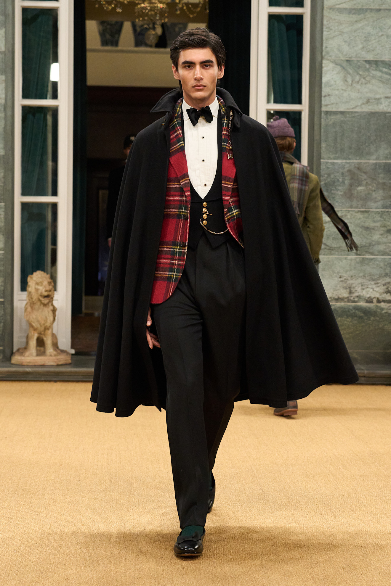 Классический наряд с черным плащом и клетчатым жилетом, завершенный строгими брюками и лакированными туфлями.