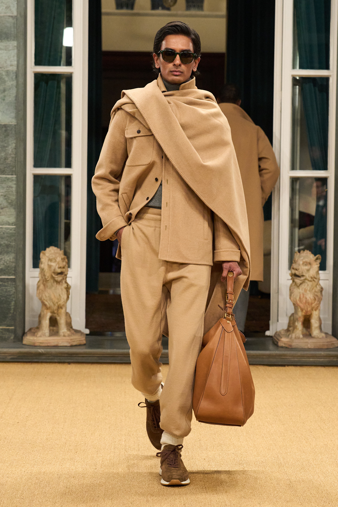 Модель в бежевом костюме с объемным шарфом и стильной сумкой, создающая уютную атмосферу осени