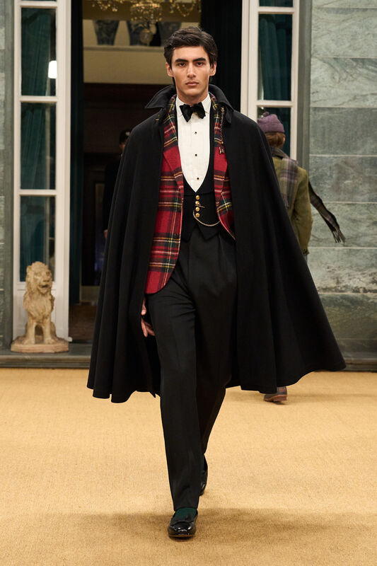 Классический наряд с черным плащом и клетчатым жилетом, завершенный строгими брюками и лакированными туфлями.