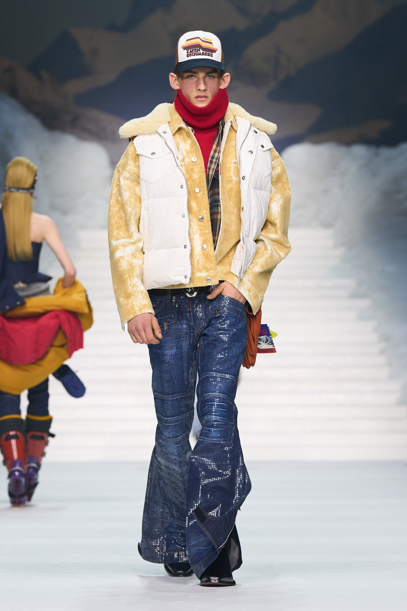 Комбинация светлого жилета и яркого свитера, дополненная стильной кепкой и джинсами с эффектом потертости