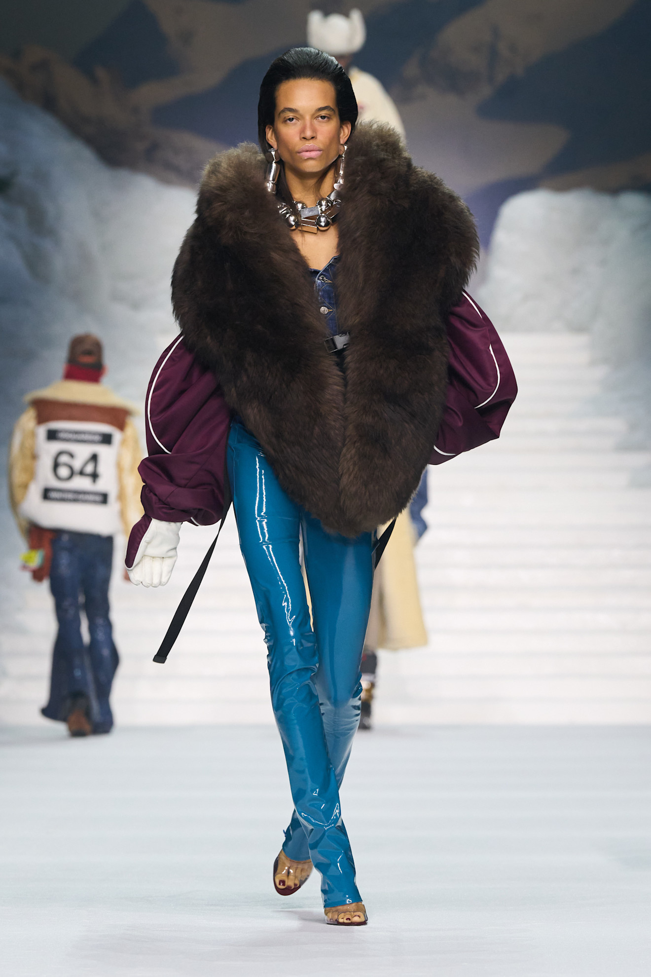 Объемный меховой палантин в сочетании с блестящими синими брюками и массивными украшениями создает эффектный зимний образ