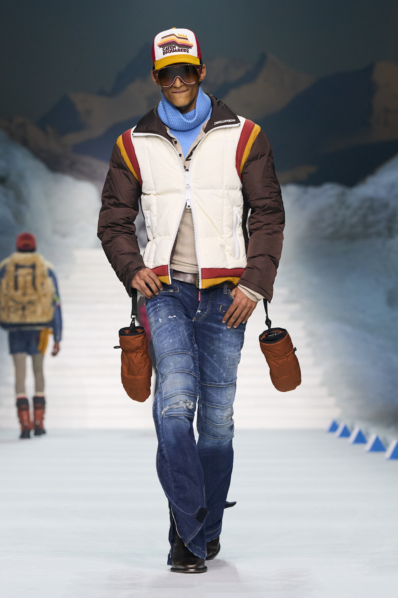 Модель в утепленной куртке с контрастными вставками и джинсах, дополняет образ стильной кепкой и солнцезащитными очками