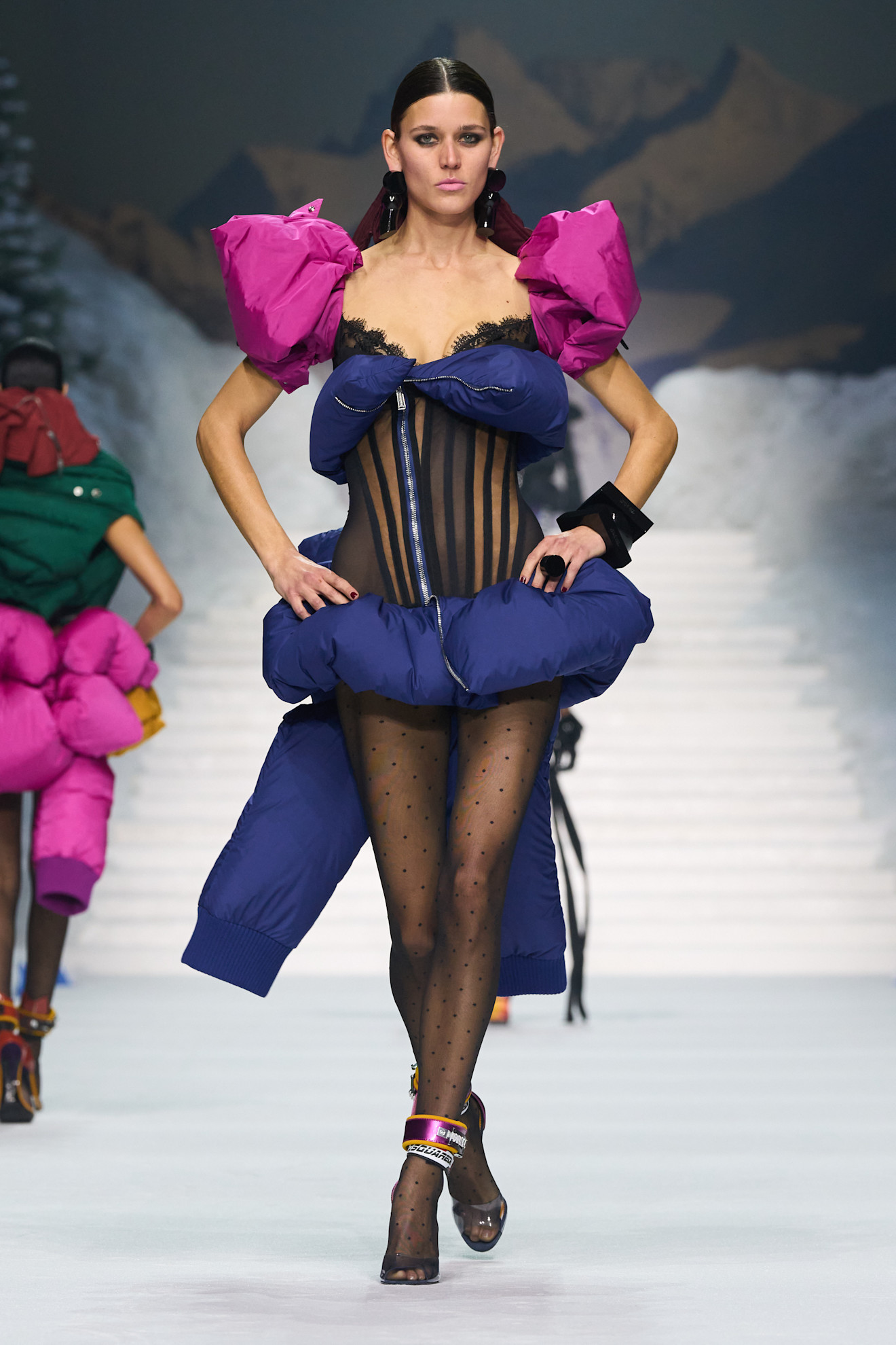 Модель в наряде с пышными розовыми рукавами и темно-синим низом, подчеркивающим стройные ноги в сетчатых колготках