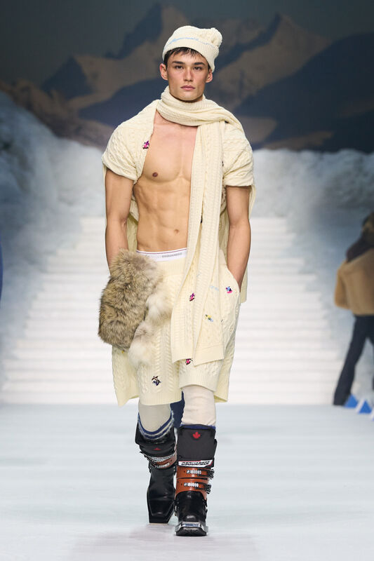 Элегантный светлый свитер с узором и шарфом, подчеркивающий спортивную фигуру, завершает образ меховая сумка и зимние ботинки