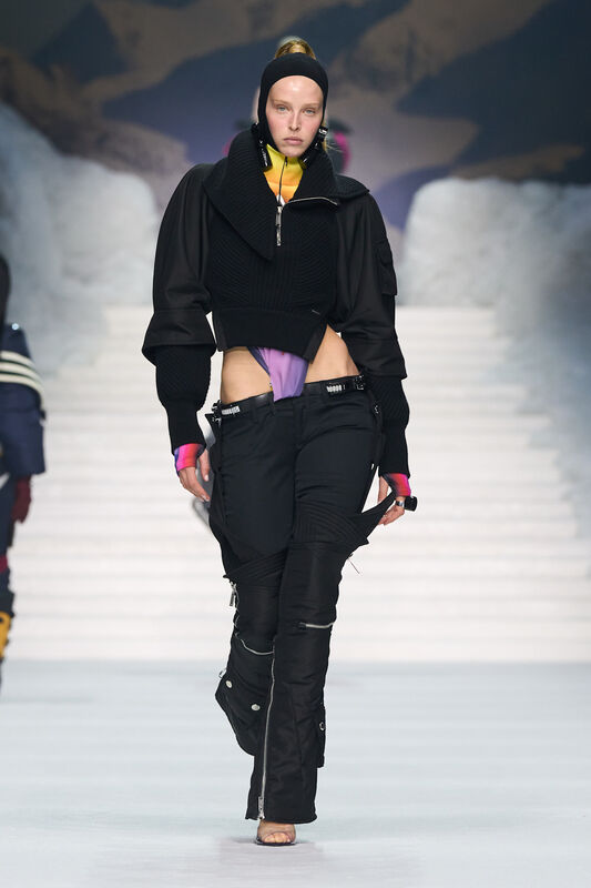 Черный свитер с крупным воротником и стильные брюки с разрезами, подчеркивающие силуэт, на фоне зимнего ландшафта