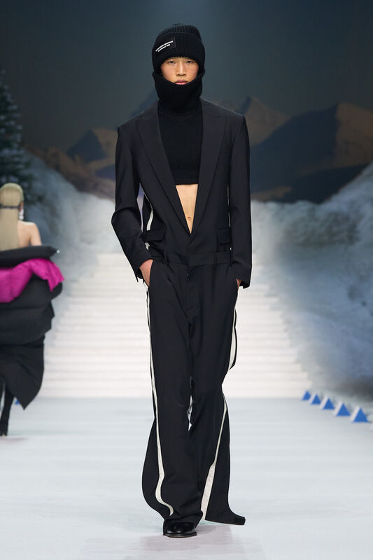 Элегантный черный костюм с укороченным свитером и шапкой, создающий контраст между формальным и спортивным стилем