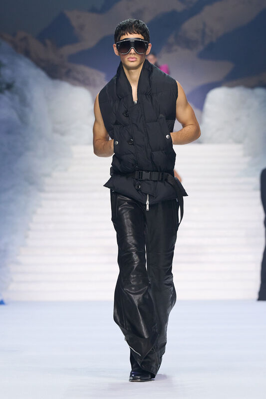 Черный жилет с пуховиками и кожаные брюки, дополненные массивными очками, подчеркивают мужественность и современный стиль