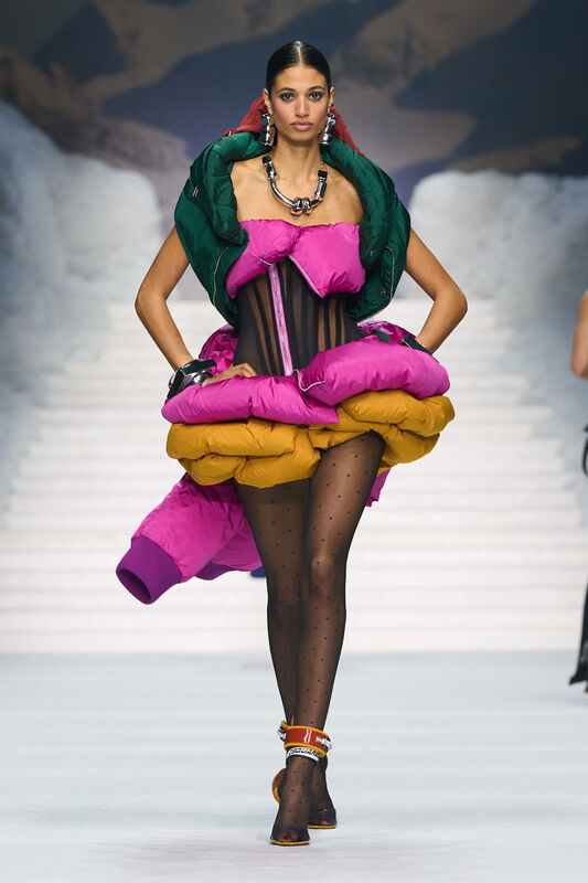 Яркое платье с объемными фиолетовыми и желтыми деталями, дополненное черными колготками в горошек и массивными украшениями