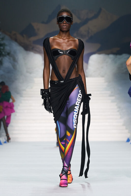 Эффектный образ с черным топом и яркими леггинсами, украшенными графикой, завершает стильные солнцезащитные очки