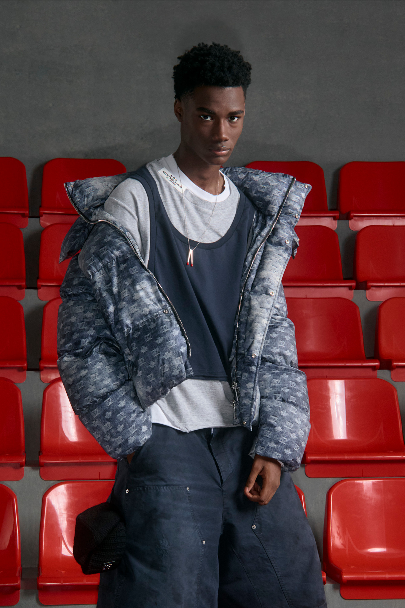 Модный спортивный стиль: многослойный образ с пуховиком и топом, выполненный в холодных тонах, на фоне красных сидений