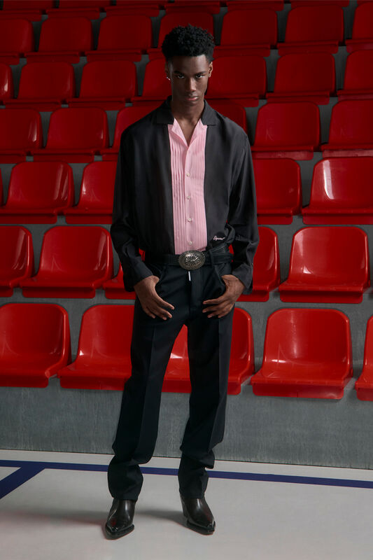 Элегантная комбинация черной и розовой рубашек с широкими брюками и стильным поясом, подчеркивающая уверенность модели