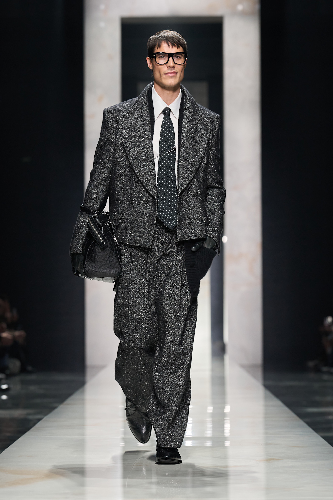 Стильный образ в блестящем сером костюме с объемными плечами и черным галстуком в горошек, создающий эффект уверенности