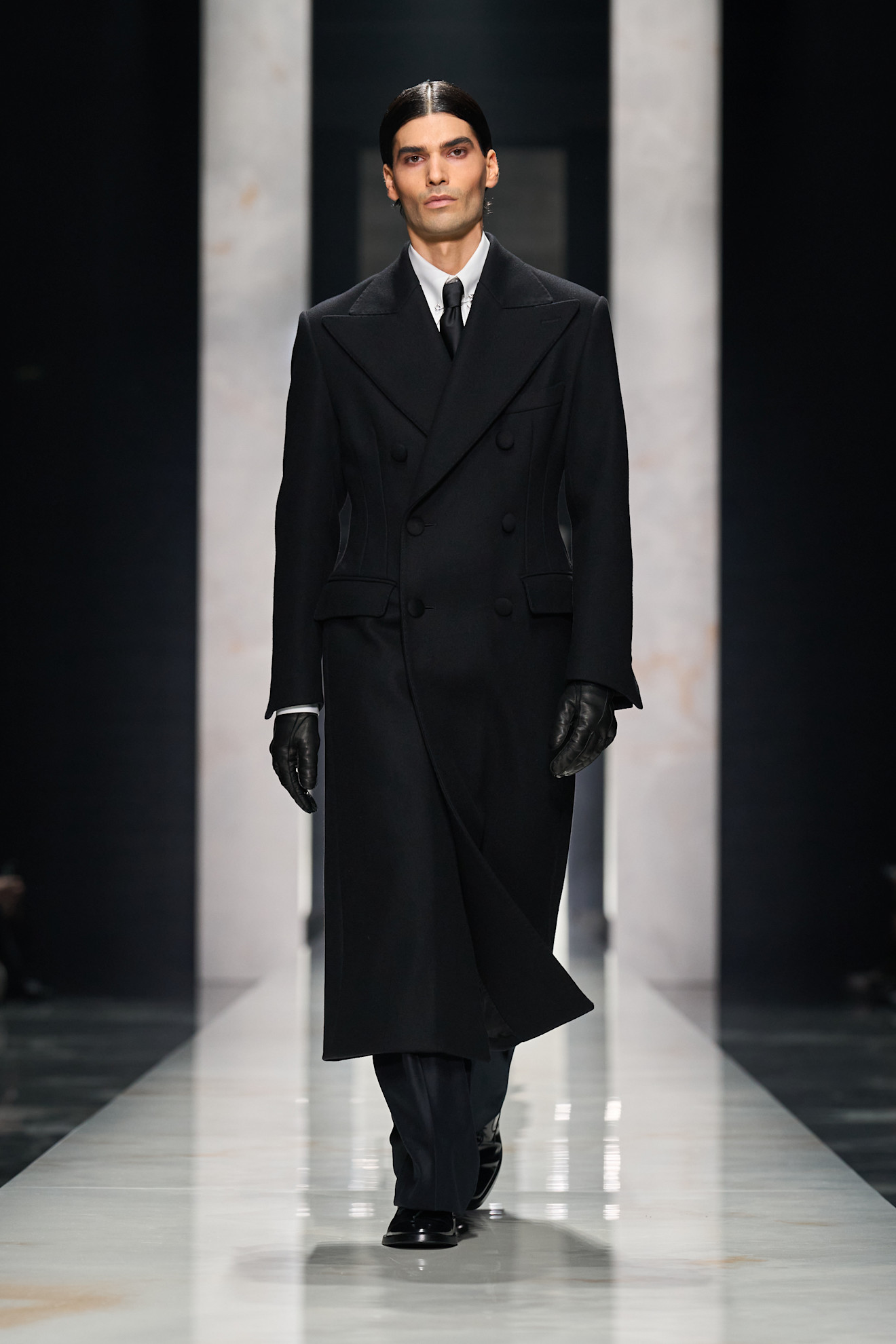 Длинный черный пальто с двойной застежкой и перчатками, придающее образу строгость и элегантность в зимнем сезоне