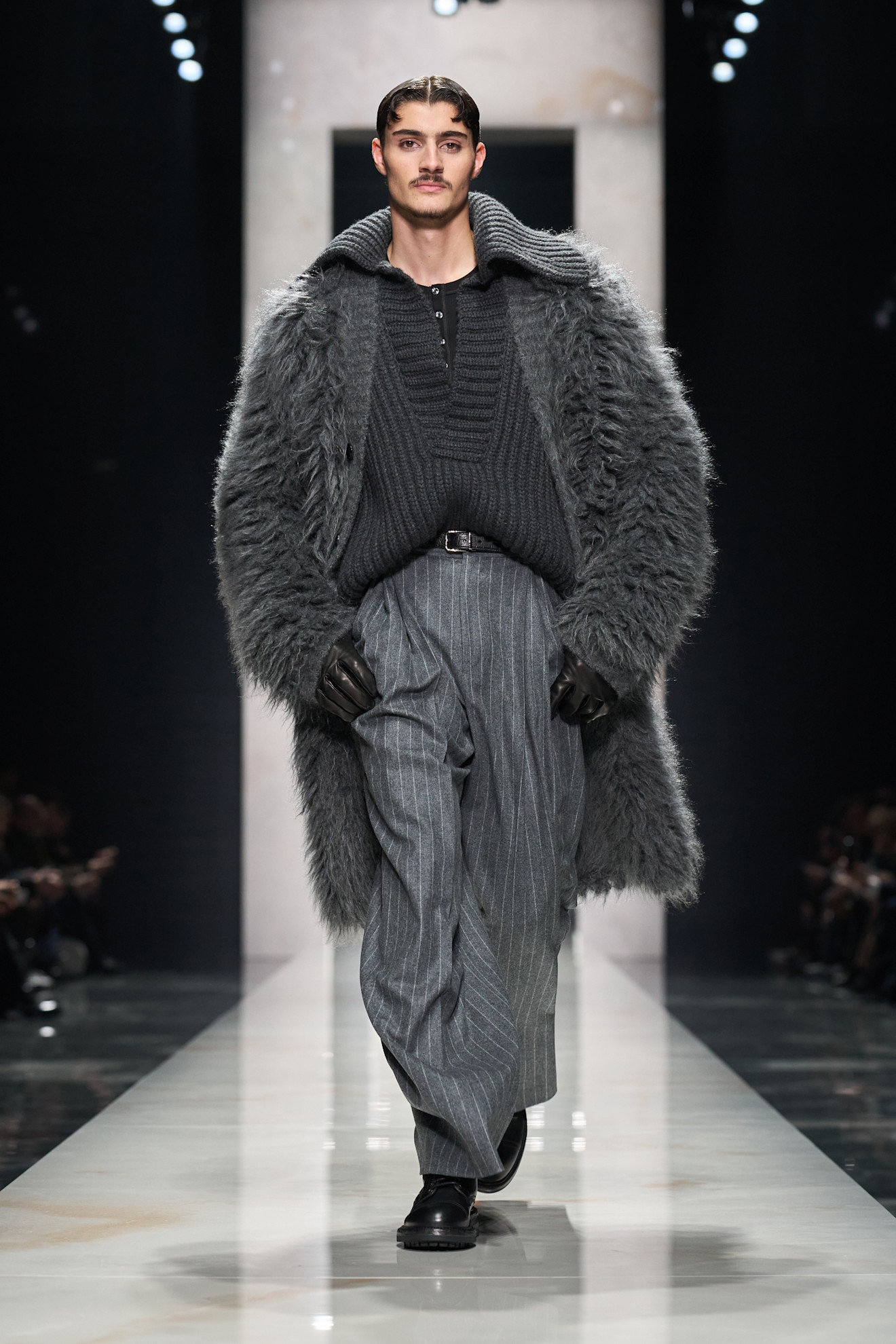 Мягкий серый свитер с крупной вязкой под объемным меховым пальто, дополненный полосатыми брюками