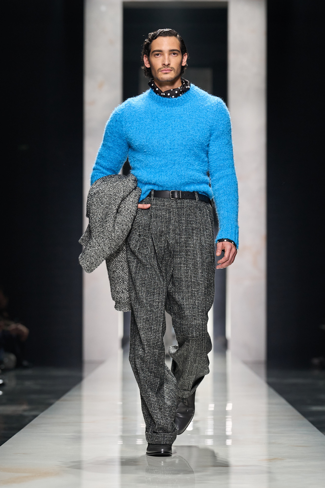 Яркий синий свитер с текстурой, гармонирующий с черно-белыми брюками в клетку, подчеркивает уверенность модели