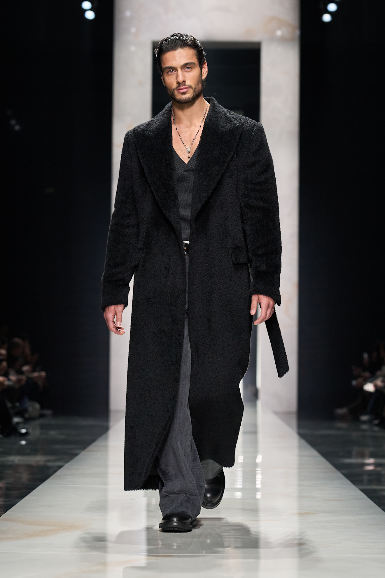 Объемный черный пальто с текстурированной поверхностью, надетый на облегающий топ и широкие брюки