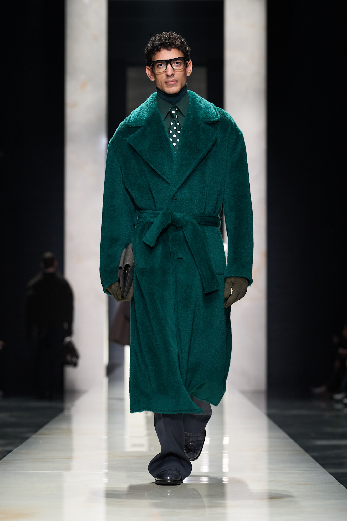 Модель в уютном зелёном пальто с поясом и стильными очками, сочетая комфорт и элегантность в осеннем образе