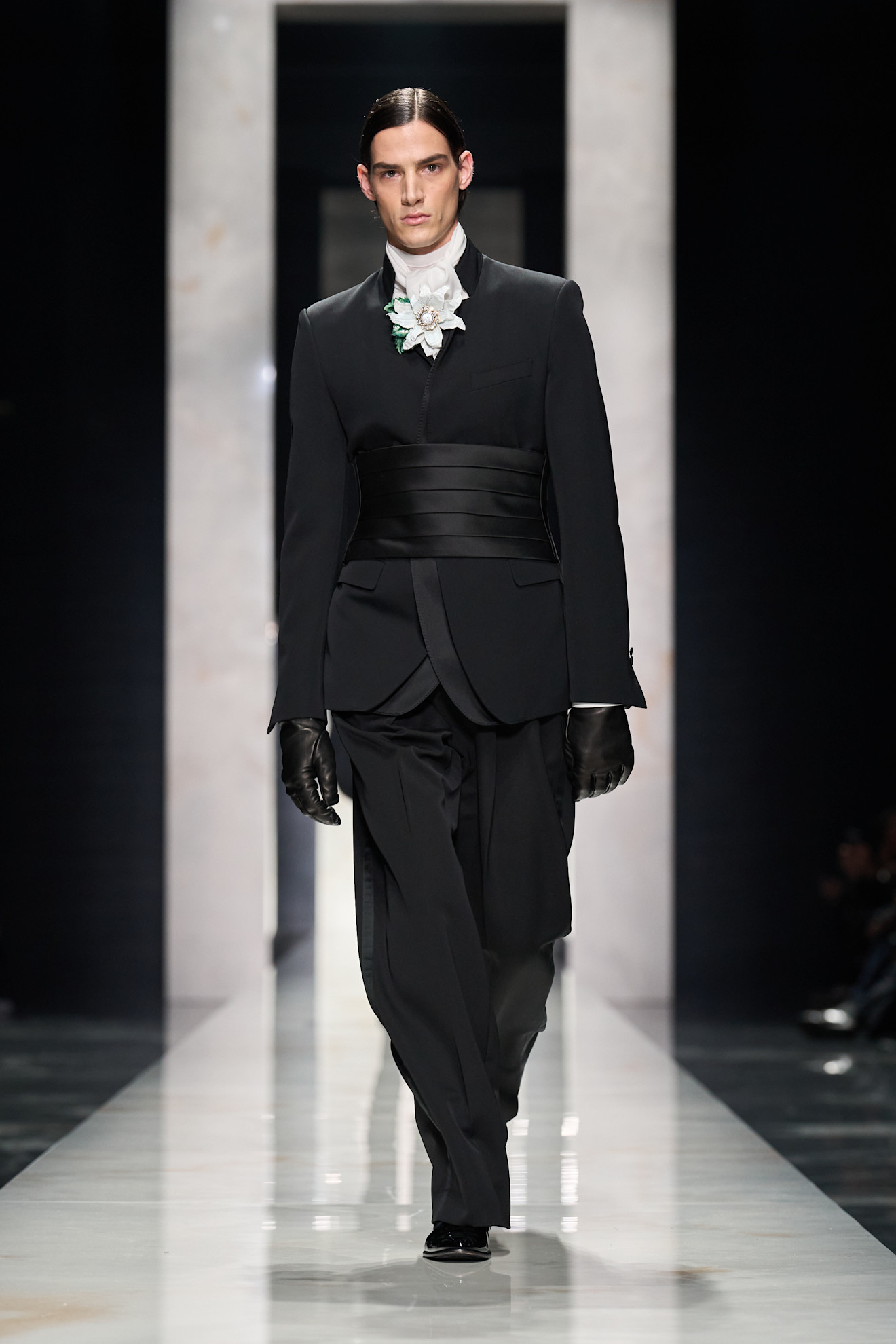 Строгий черный костюм с широким поясом и цветочной брошью, создающий эффектный контраст с белым воротником