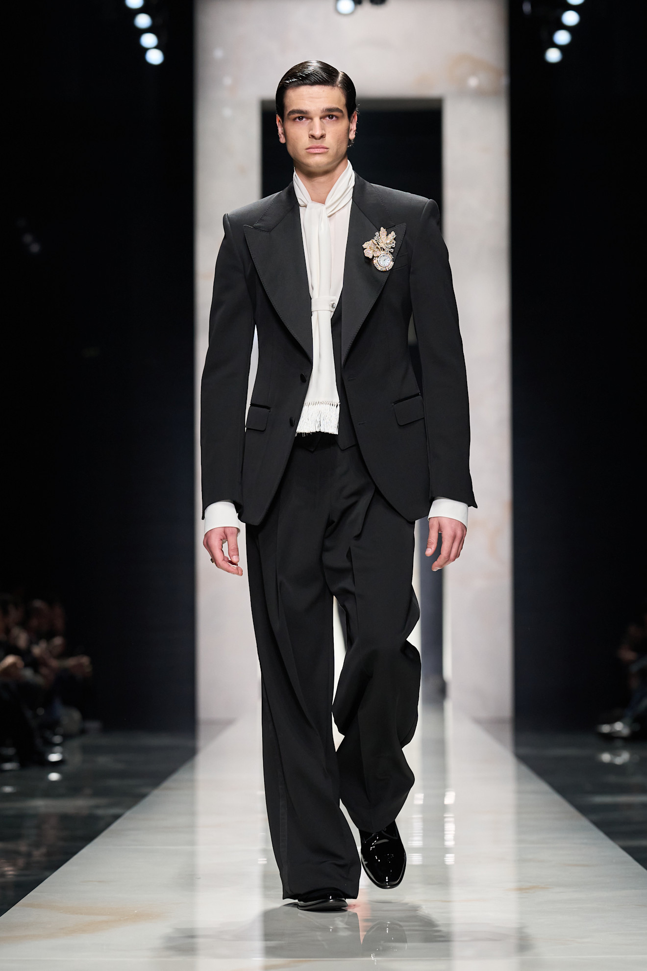 Элегантный черный смокинг с белым бантом и брошей, подчеркивающий строгость и стиль Dolce & Gabbana осени-зимы 2026