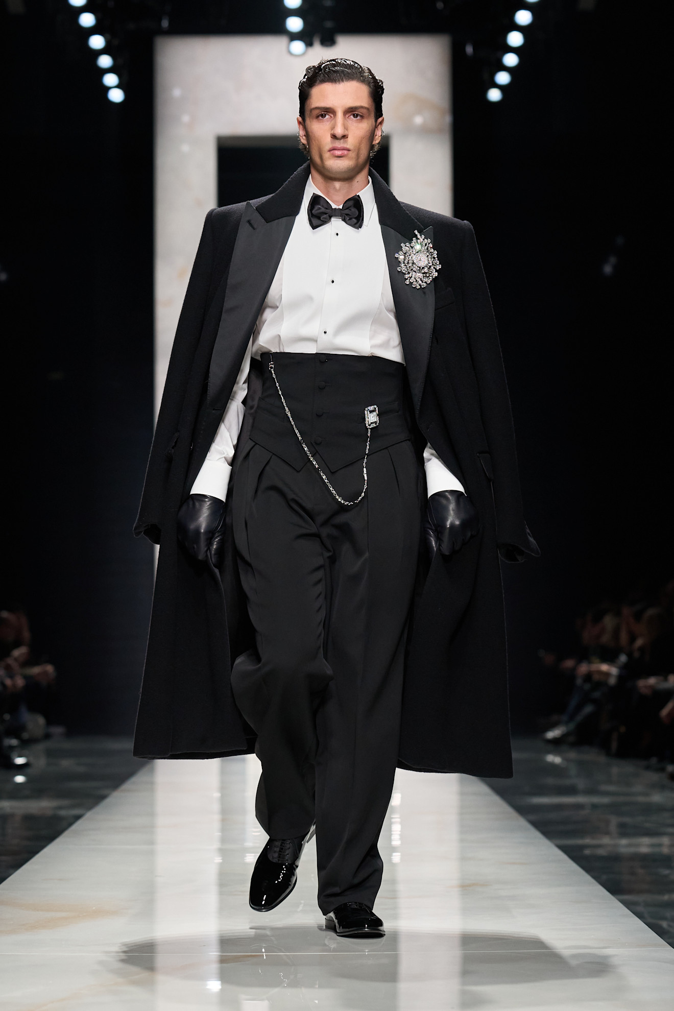 Роскошный черный плащ с длинным силуэтом и изящной брошей, создающий эффектный образ для вечернего выхода