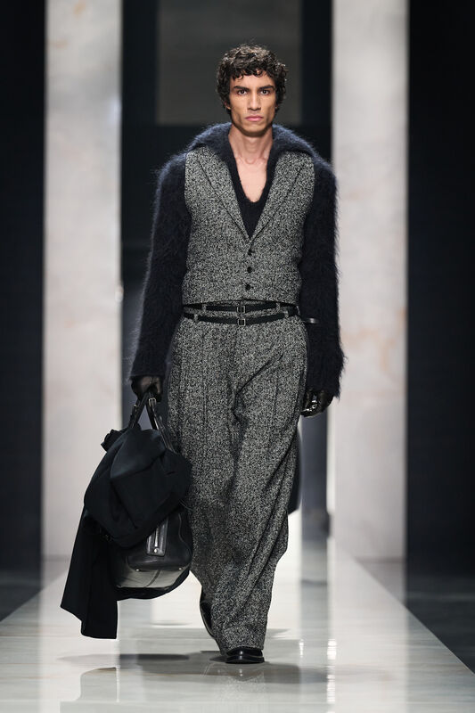 Модель в сером костюме с объемными рукавами, дополненном черной сумкой, создает стильный образ для осени 2026 года