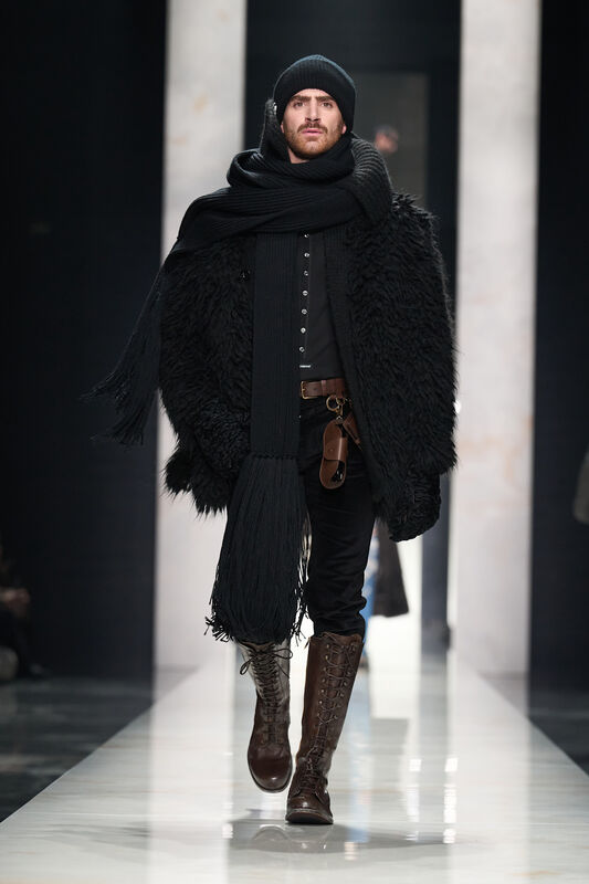 Модель в черном наряде с объемным пальто и шапкой, завершает образ коричневыми высокими ботинками, создавая атмосферу уюта