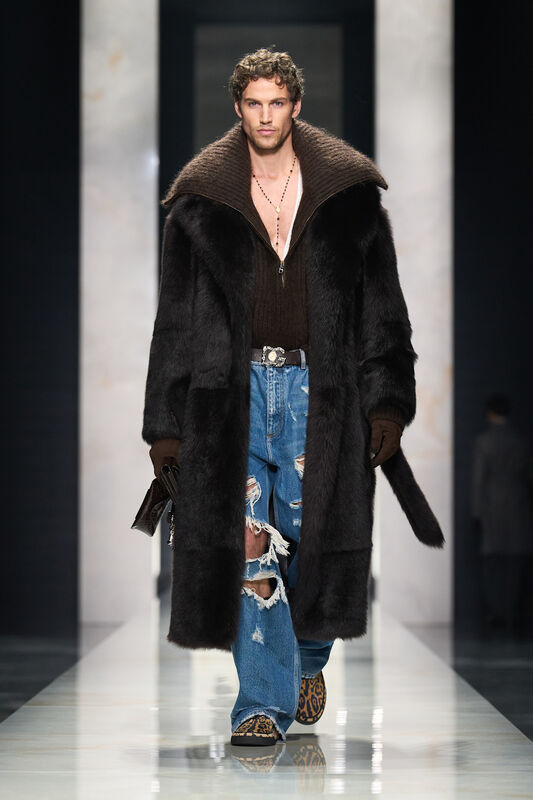 Модель в роскошном черном меховом пальто и рваных джинсах, дополняет образ леопардовыми кроссовками и цепочкой на шее