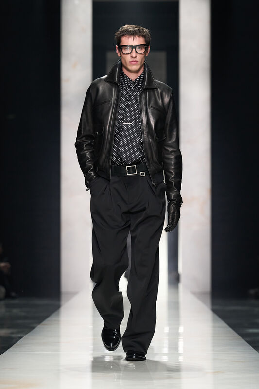 Кожаная куртка и рубашка в горошек создают смелый образ, дополненный широкими брюками и крупными очками, подчеркивающими индивидуальность