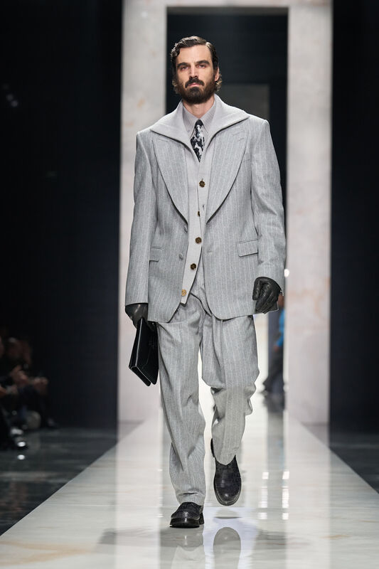 Стильный мужской костюм в светло-сером цвете с полосками, дополненный перчатками и сумкой, создает атмосферу элегантности