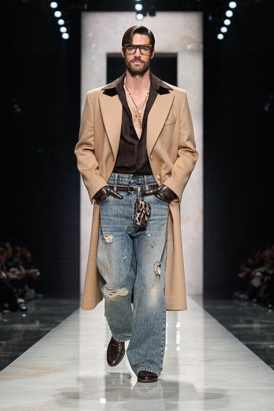 Элегантный образ с бежевым пальто, рваными джинсами и глубоким декольте, дополненный крупными очками и цепочкой