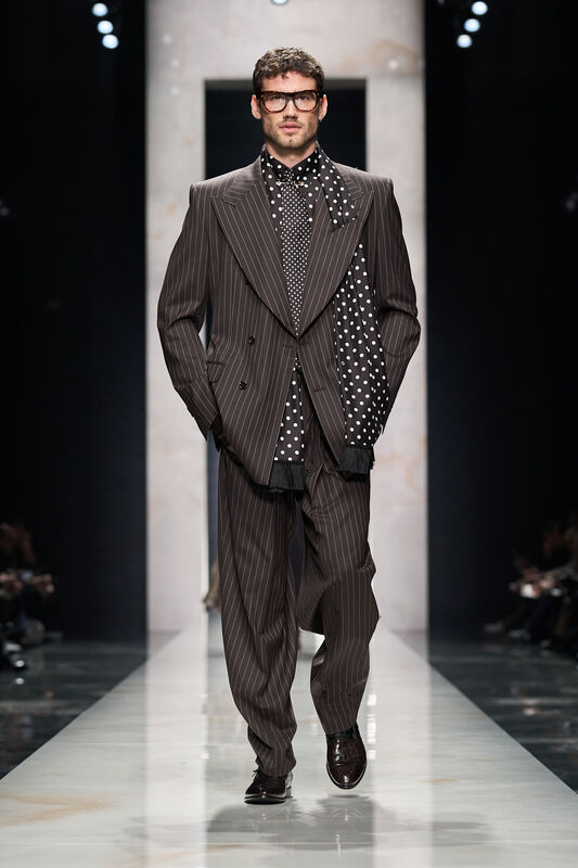 Строгий двубортный пиджак с вертикальными полосками и полка с горошком, создающий эффектный контраст на подиуме