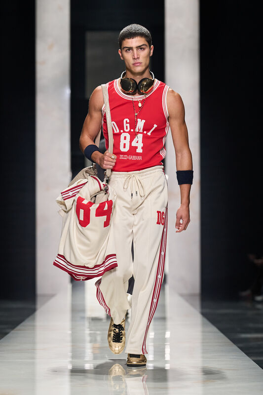 Яркий спортивный комплект с красным топом и светлыми брюками, дополненный наушниками и стильной сумкой