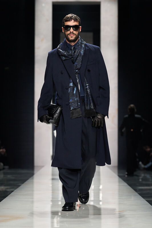 Элегантный образ в темно-синем пальто с шарфом, дополненный стильными очками и кожаной сумкой