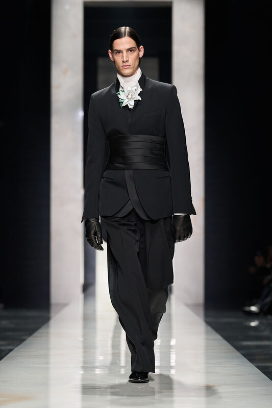 Строгий черный костюм с широким поясом и цветочной брошью, создающий эффектный контраст с белым воротником