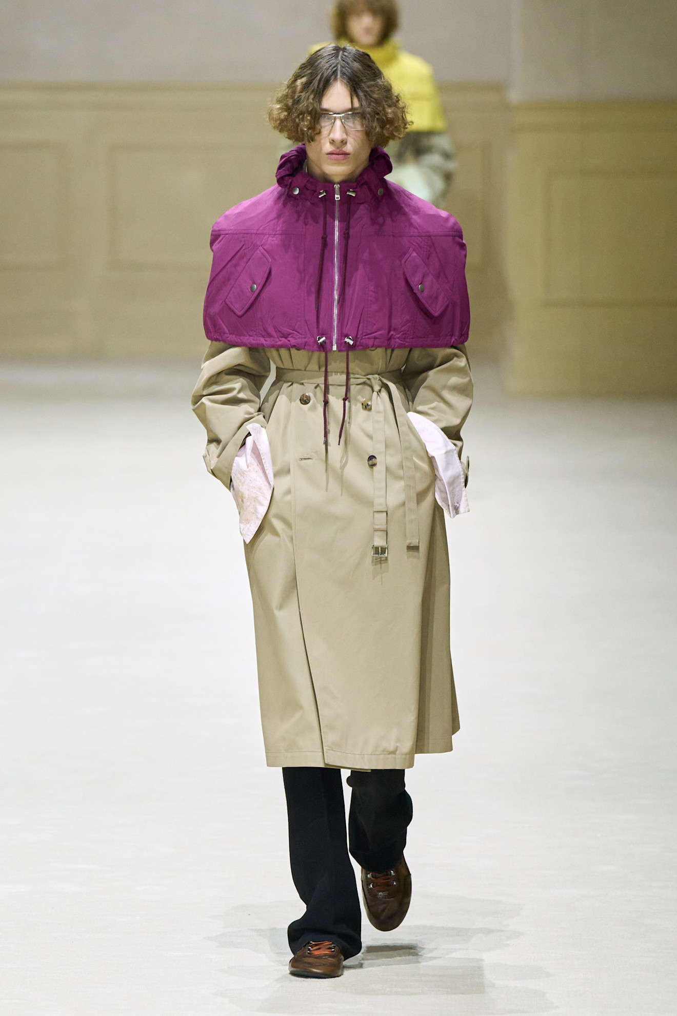 Модель в бежевом тренче с фиолетовым верхом, создающим контраст, завершает образ стильными туфлями и очками