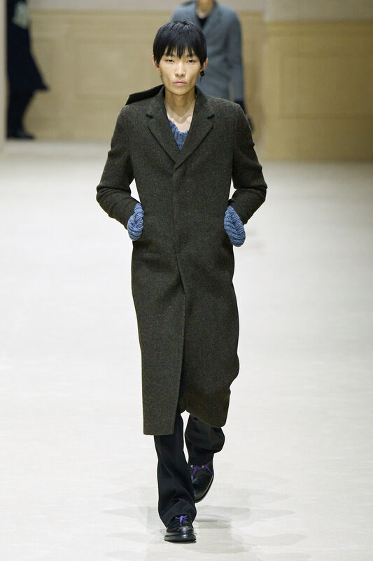 Длинный коричневый пальто с текстурой, дополненный вязанными перчатками, придающими образу уют и стиль