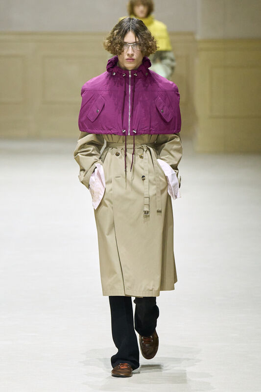 Модель в бежевом тренче с фиолетовым верхом, создающим контраст, завершает образ стильными туфлями и очками