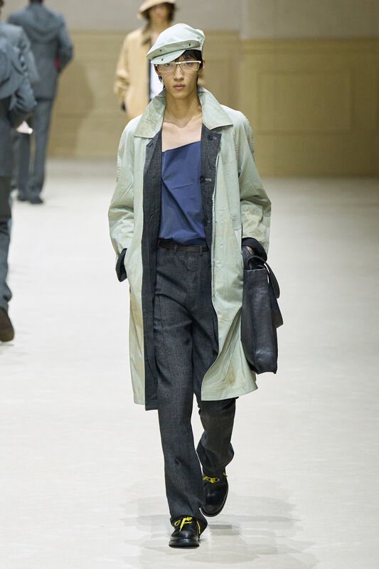 Светло-зеленый тренч с асимметричным верхом и стильной кепкой, дополненный темными брюками и сумкой