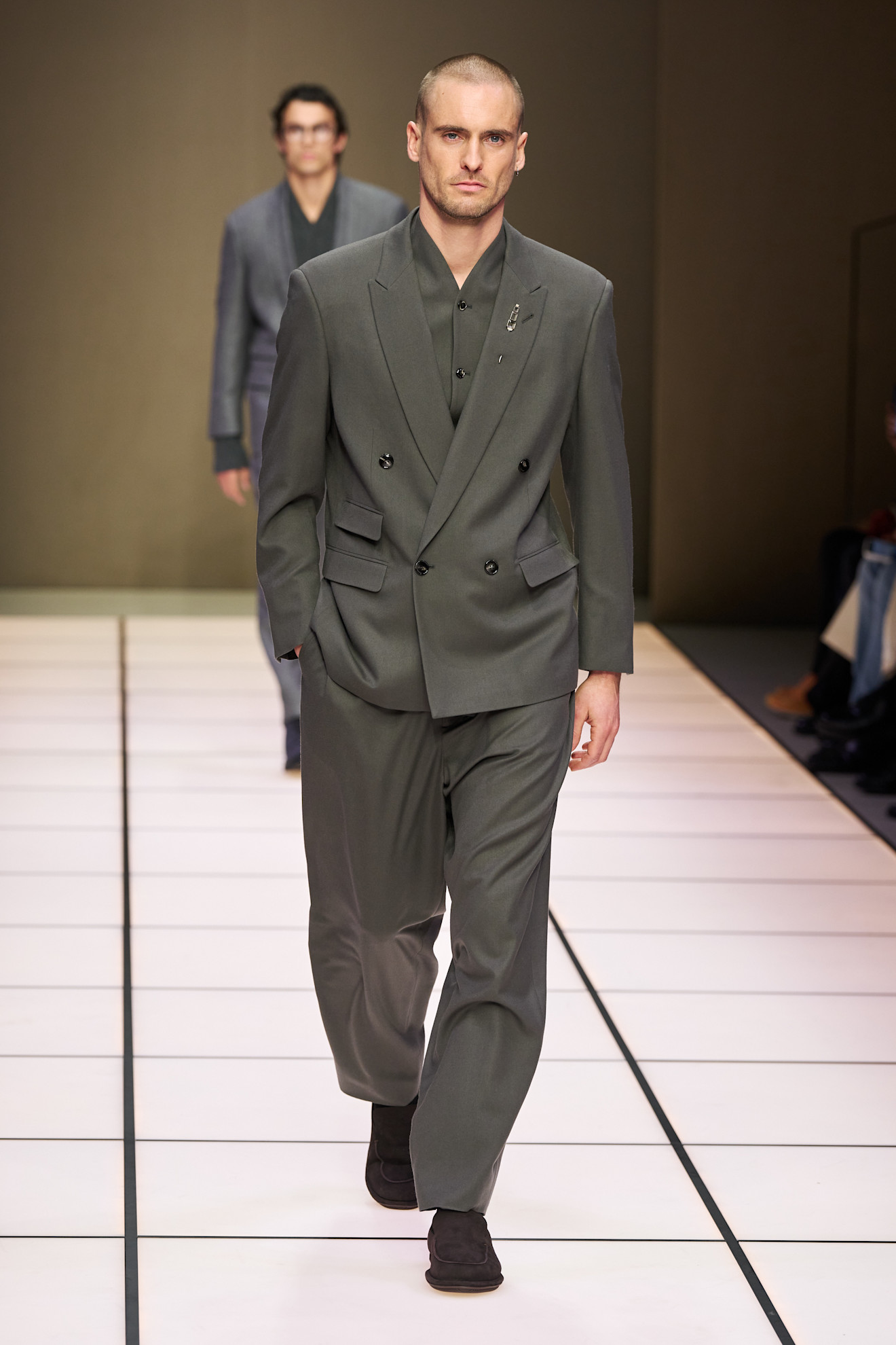 Строгий серый костюм с двойной застежкой, дополненный элегантной брошью, создает атмосферу уверенности и стиля