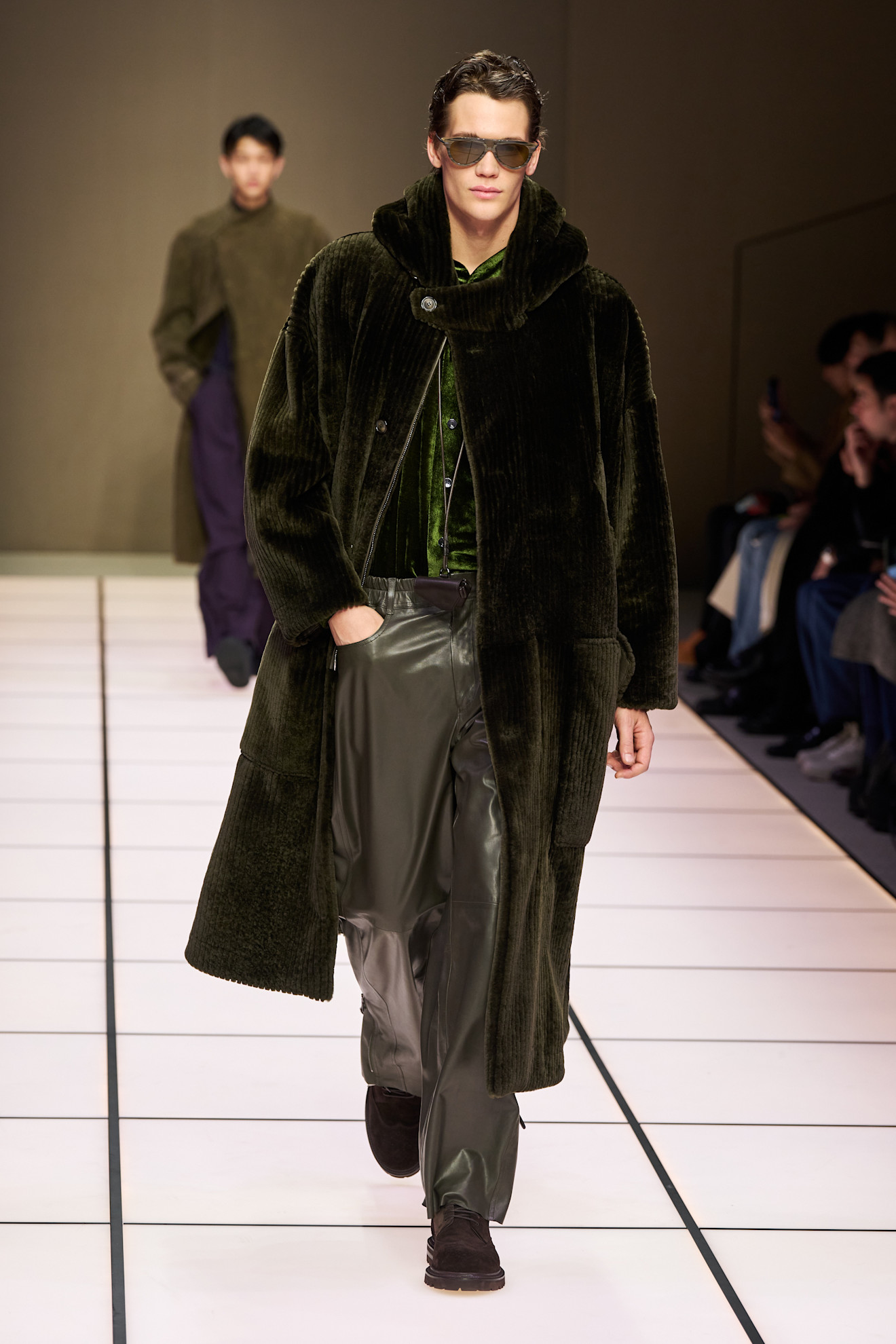 Объемный темно-зеленый пальто из мягкого велюра, под которым виден блестящий изумрудный топ и кожаные брюки в тон