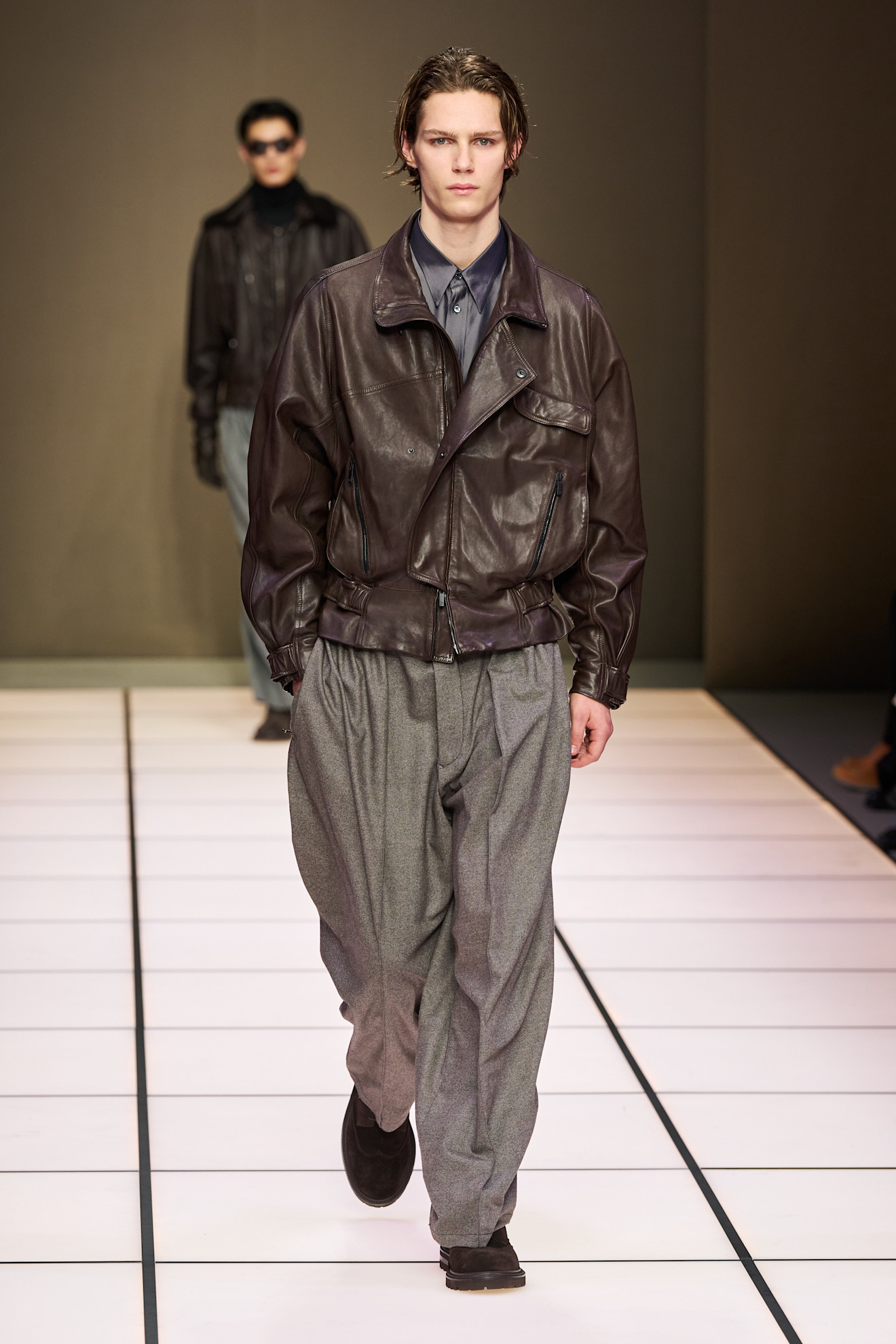 Легкая коричневая кожаная куртка в сочетании с серыми брюками, создающими эффектный контраст и стильный городской образ