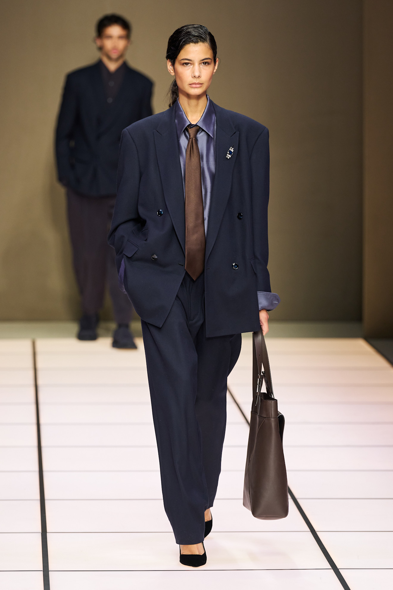 Элегантный женский костюм с объемным пиджаком и коричневым галстуком, подчеркивающий силуэт и стиль