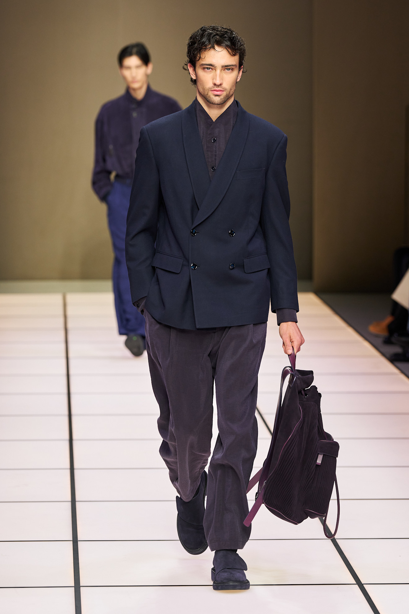 Мужская двойка в темно-синем цвете с текстурированным пиджаком, дополненная стильной сумкой и уверенным взглядом