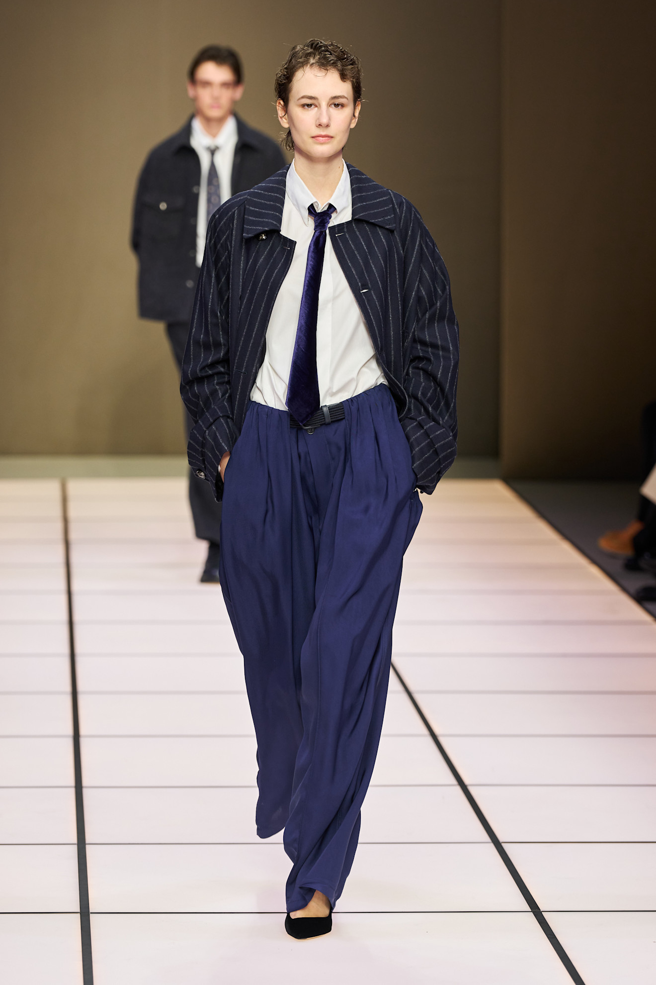 Женский образ с полосатой курткой и широкими брюками, дополненный строгим галстуком, создает современный и стильный вид