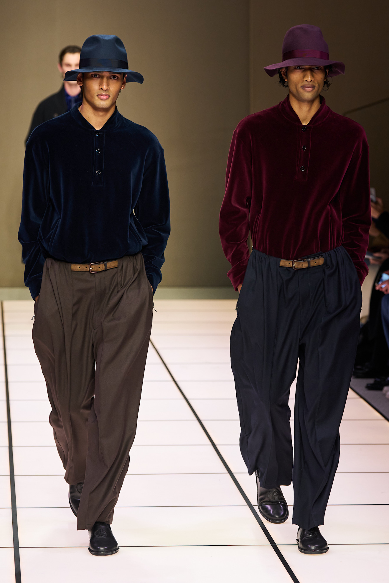 Два мужчины в бархатных футболках глубоких оттенков, с широкими брюками и стильными шляпами, создают атмосферу уюта