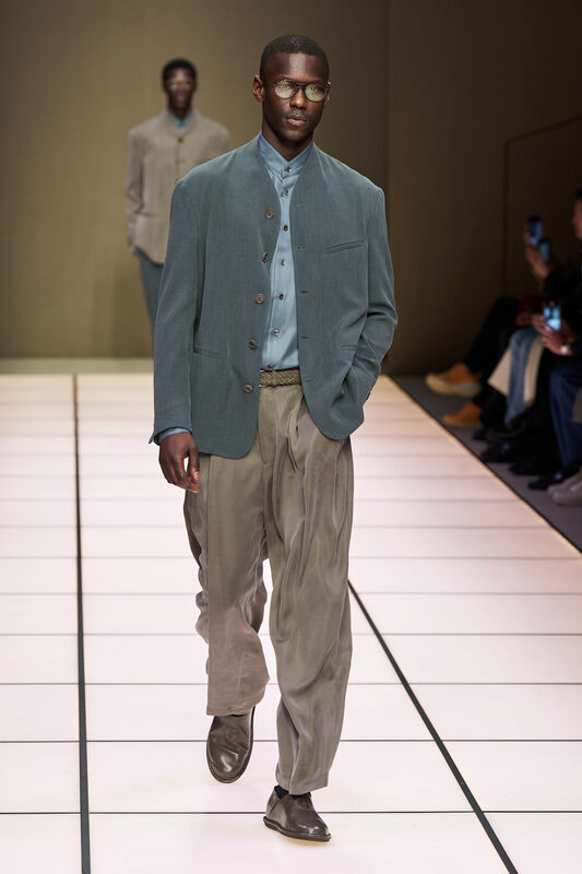 Модель в мягком жакете и светлой рубашке, дополненной свободными брюками, отражает современный подход Armani к классике