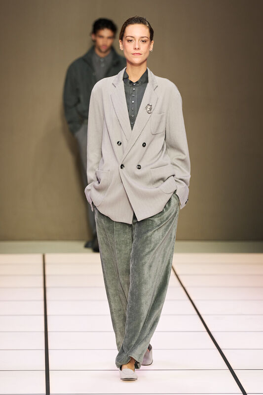 Женская модель в светло-сером пиджаке с двойной застежкой и широких брюках, создающих расслабленный образ